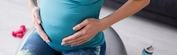 Vue recadrée d'une sportive enceinte faisant de l'exercice sur un ballon de fitness, bannière — Photo de stock