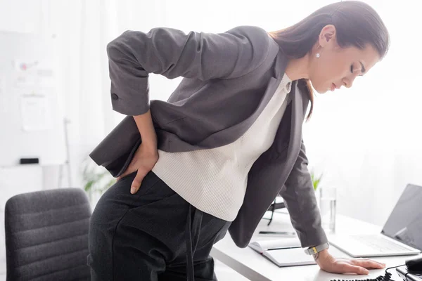 Mulher de negócios grávida que sofre de dor e inclinação na mesa no escritório — Fotografia de Stock