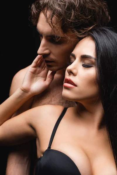 Brunette woman touching face of shirtless man isolated on black — Stock Photo