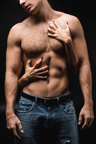 Cropped view of woman scratching chest of muscular man on black — Stock Photo