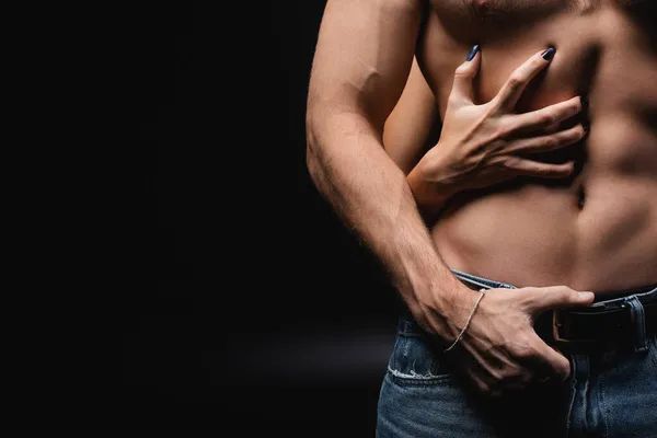 Recortado vista de la mujer rascarse el pecho de muscular novio en negro — Stock Photo