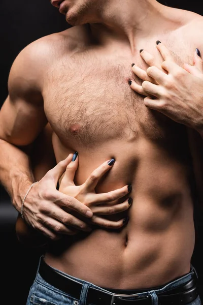 Recortado vista de la mujer rascarse el pecho de muscular novio en negro — Stock Photo