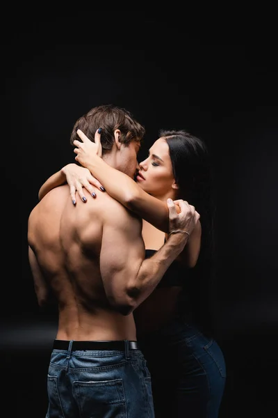 Young sexy couple with closed eyes kissing while standing on black — Stock Photo