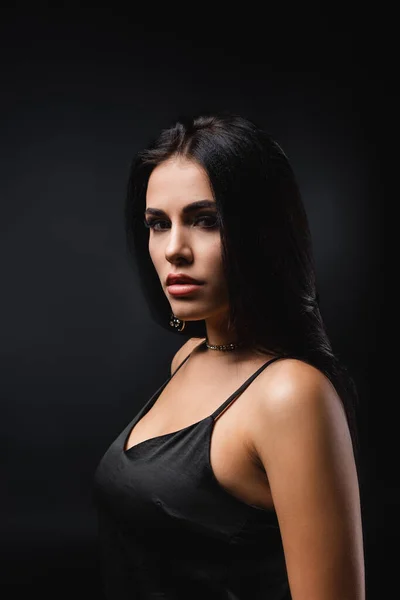 Brunette young woman in slip dress looking at camera isolated on black — Stock Photo