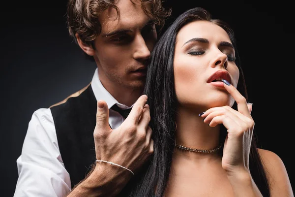 Man seducing sexy brunette woman on black — Stock Photo