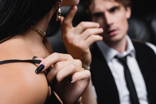 Young woman adjusting strap on dress near blurred boyfriend — Stock Photo