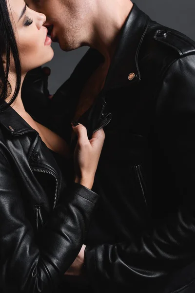 Sexy young couple in leather jackets kissing isolated on grey — Stock Photo