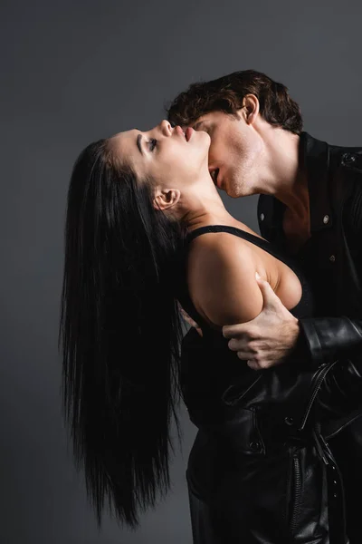 Apasionado hombre besos cuello de sexy mujer aislado en gris - foto de stock