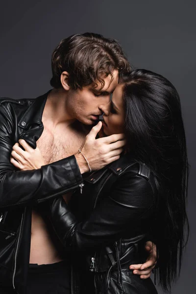 Passionate man kissing with sexy woman in leather jacket isolated on grey — Stock Photo