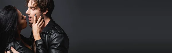 Vue latérale de l'homme passionné à bouche ouverte et femme sexy en veste en cuir isolé sur gris, bannière — Photo de stock