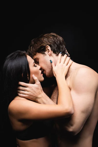 Side view of young couple with closed eyes hugging while kissing isolated on black — Stock Photo