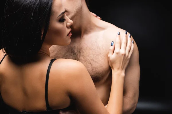 Morena mujer en ropa interior abrazando sin camisa novio en negro - foto de stock