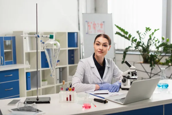 Científico mirando la cámara cerca de dispositivos y equipos médicos en el laboratorio - foto de stock