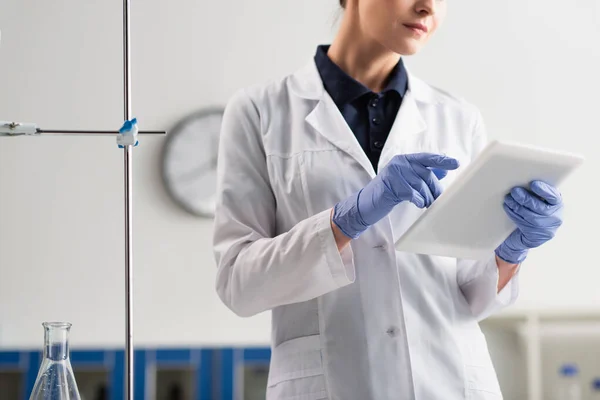 Vista recortada de científico en guantes de látex usando tableta digital en laboratorio - foto de stock