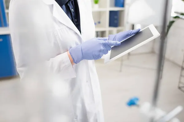 Vista recortada de científico en guantes de látex usando tableta digital en laboratorio - foto de stock