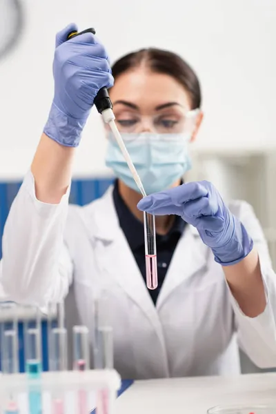 Scientist in latex gloves holding electronic pipette and test tube in laboratory — Stock Photo