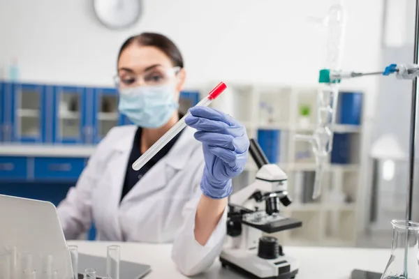 Pcr test in hand of blurred scientist near laptop and microscope in laboratory — Stock Photo