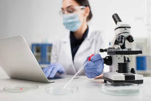 Vergrabener Wissenschaftler hält PCR-Test in der Nähe von Petrischalen und Laptop im Labor — Stockfoto