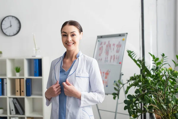 Médecin joyeux en manteau blanc regardant la caméra dans le laboratoire — Photo de stock