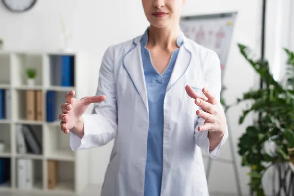 Обрізаний вид розмитого лікаря, який показує щось руками в клініці — стокове фото