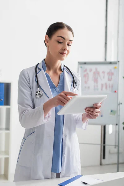 Brunette doctor with stethoscope using digital tablet in clinic — Stock Photo