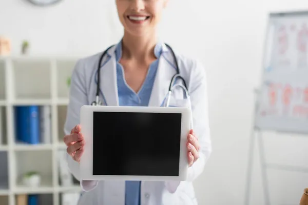 Ausgeschnittene Ansicht des digitalen Tablets mit leerem Bildschirm in den Händen eines lächelnden Arztes im Krankenhaus — Stockfoto