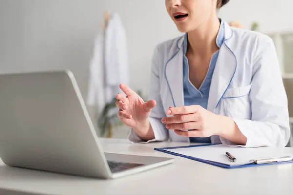 Vista ritagliata del medico che effettua videochiamate vicino agli appunti e al laptop in ospedale — Foto stock