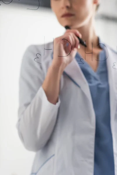 Partial view of chemist standing near formulas on glass board in lab — Stock Photo