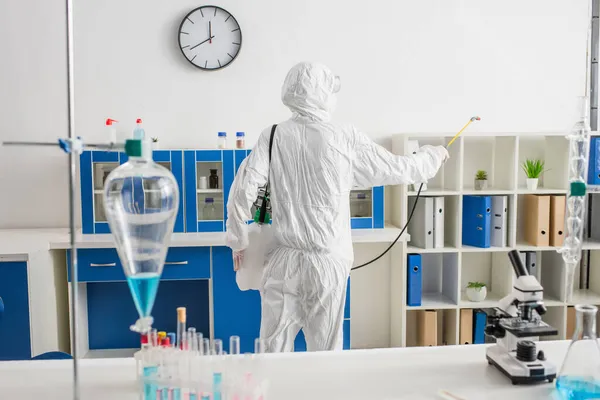 Back view of doctor in hazmat suit making disinfection of laboratory — Stock Photo