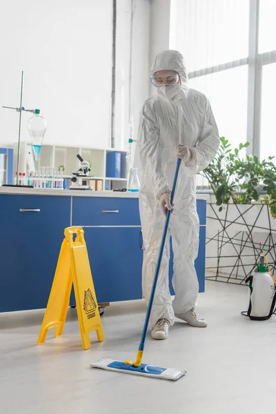 Doctor in hazmat suit cleaning floor with mop in medical laboratory — Stock Photo