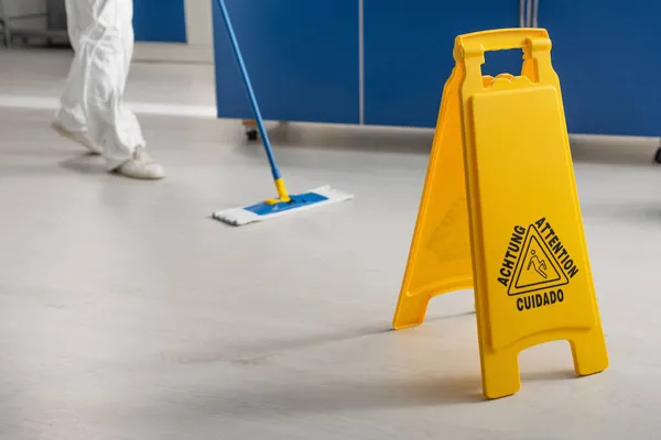 Ausgeschnittener Blick auf Arzt, der Boden im Labor in der Nähe der Aufmerksamkeitstafel wischt — Stockfoto