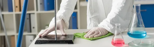 Cropped view of doctor wiping desk in lab near flasks and petri dishes, banner — Stock Photo