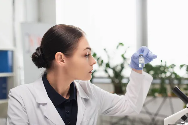 Scientist in latex glove holding coronavirus vaccine in laboratory — Stock Photo