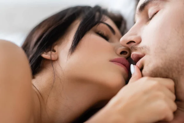 Mujer morena desnuda tocando los labios del novio con los ojos cerrados - foto de stock