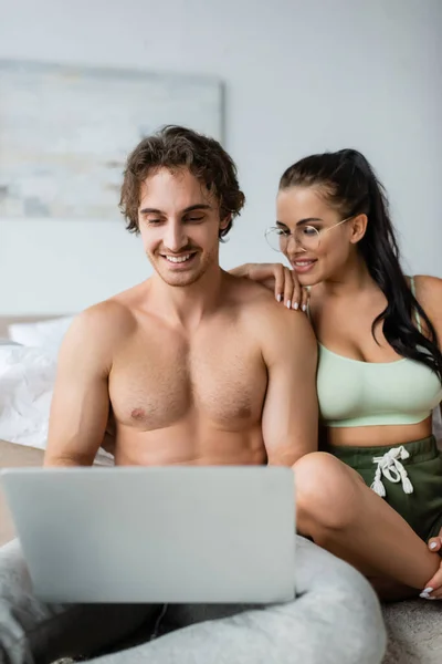Young sexy couple using blurred laptop in bedroom at home — Stock Photo