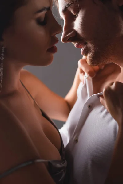 Side view of sexy woman in dress unbuttoning shirt on boyfriend at home — Stock Photo