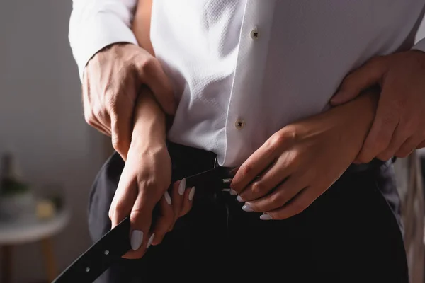 Cropped view of woman taking off waist belt from boyfriend at home — Stock Photo