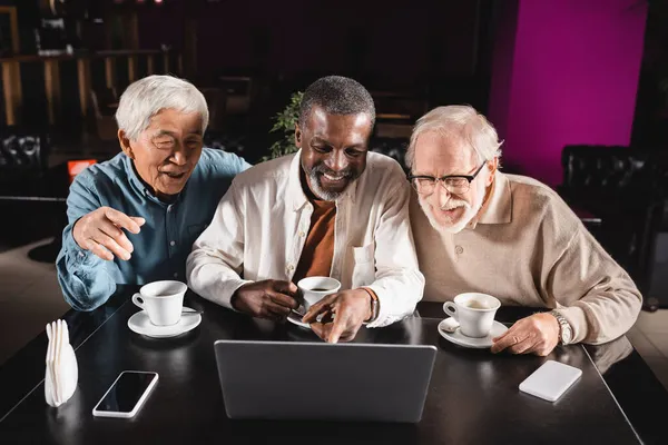 African american man pointing at laptop during video call near senior multiethnic friends — Stock Photo