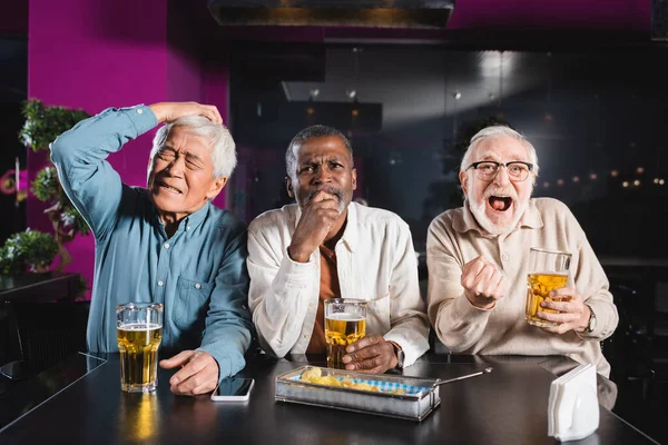 Verblüffter und glücklicher Senior zeigt Siegergeste beim Fußballgucken mit aufgebrachten interrassischen Freunden in der Kneipe — Stockfoto