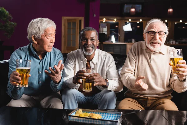 Cheerful african american man watching football match with worried interracial friends in sports bar — Stock Photo