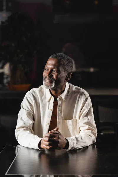 Glücklicher älterer afrikanisch-amerikanischer Mann schaut weg, während er in der Bar sitzt — Stockfoto
