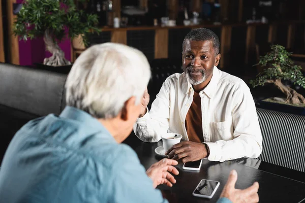 Senior african man talking to blurred friend during meeting in bar — Stock Photo