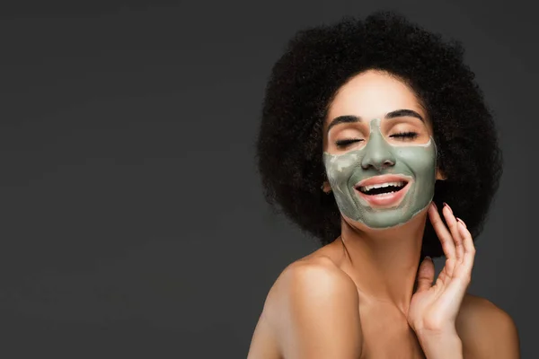 Mulher americana africana feliz com máscara de barro no rosto sorrindo com os olhos fechados isolados no cinza — Fotografia de Stock