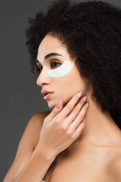 Joven africano americano mujer en ojo parche tocando cara aislado en gris — Stock Photo