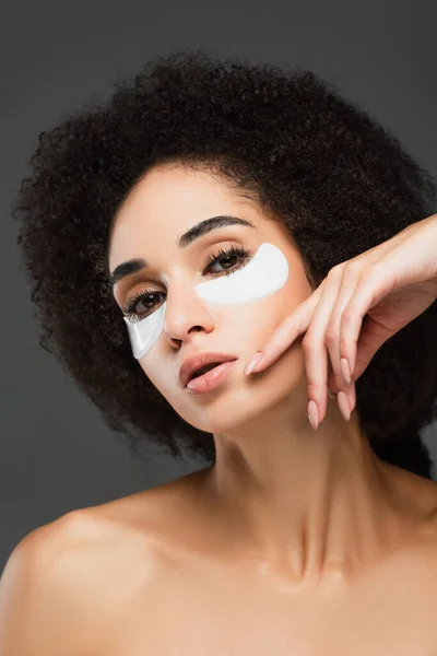 Jeune femme afro-américaine dans les yeux patchs posant avec la main près du visage isolé sur gris — Photo de stock