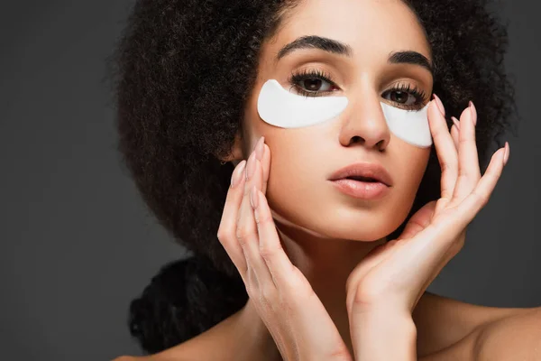 Vue rapprochée de la femme afro-américaine dans les patchs des yeux en regardant la caméra isolée sur gris — Photo de stock