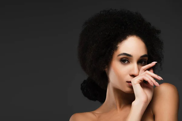Giovane donna afroamericana con spalle nude e pelle pulita che tiene la mano vicino al viso isolato sul grigio — Foto stock