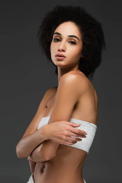 Slim african american woman in white top looking at camera isolated on grey — Stock Photo