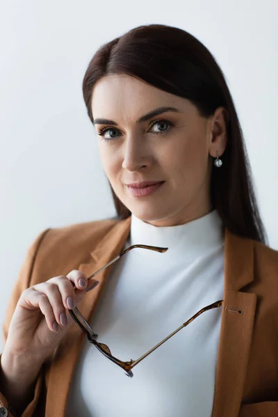 Brunette psychologist holding eyeglasses while looking at camera — Stock Photo