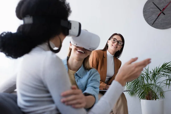 Smiling psychologist looking at interracial lesbian women gaming in vr headsets — Stock Photo